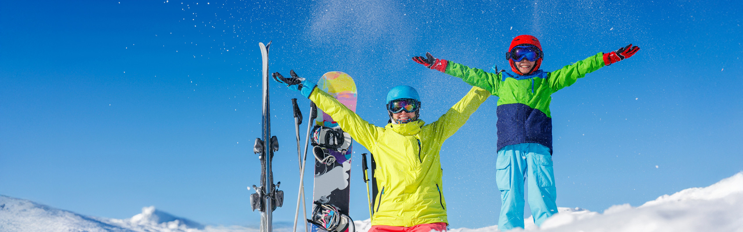 Frau und Kind in Skiausrüstung werfen Schnee in die Luft