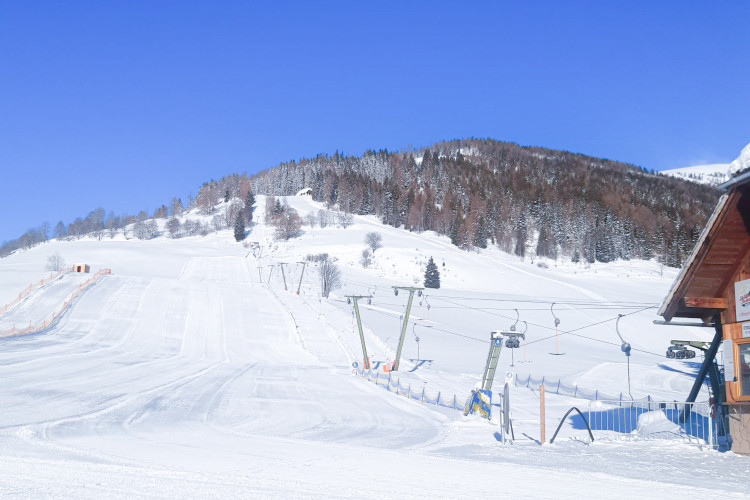 „Sonniger Wintertag im Skigebiet Krakau mit frisch präparierten Skipisten, Schleppliften und erschneiten Hängen vor blauem Himmel.